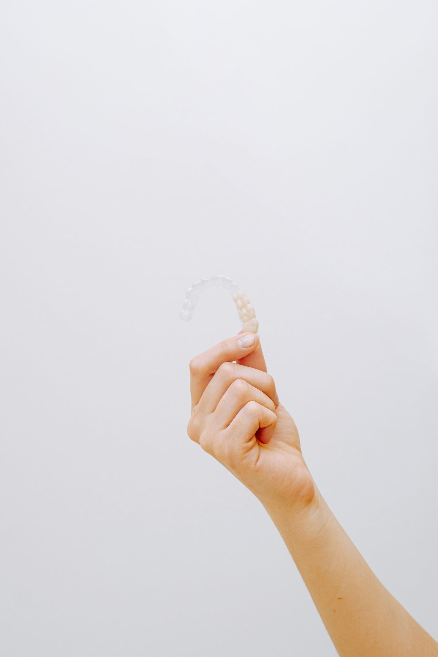 Clear dental aligner held in a hand